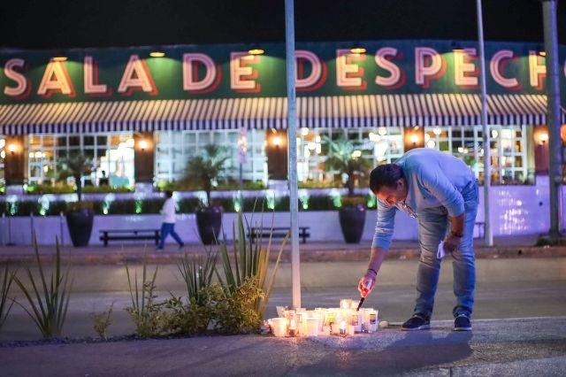 Una persona enciende una veladora frente al bar Sala de Despecho, donde tres personas fueron asesinadas