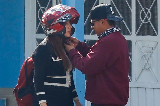 Hombre pone casco de motociclista a una mujer