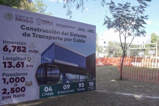 Lona con datos del cablebus de la ciudad de Puebla junto a un árbol
