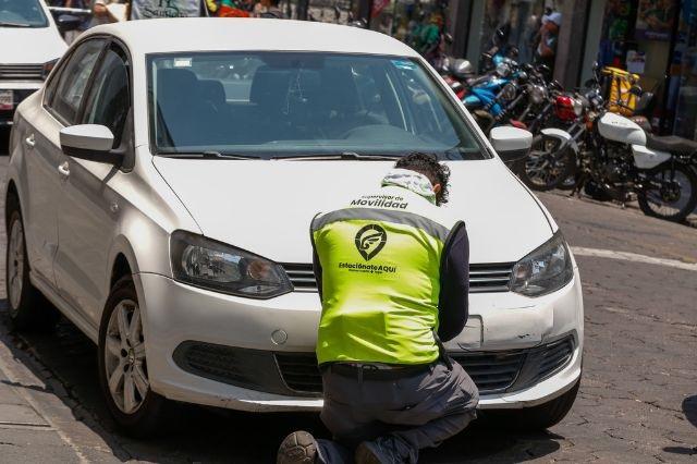 Personal del Ayuntamiento frente a un auto estacionado en un cajón de parquímetros en Puebla