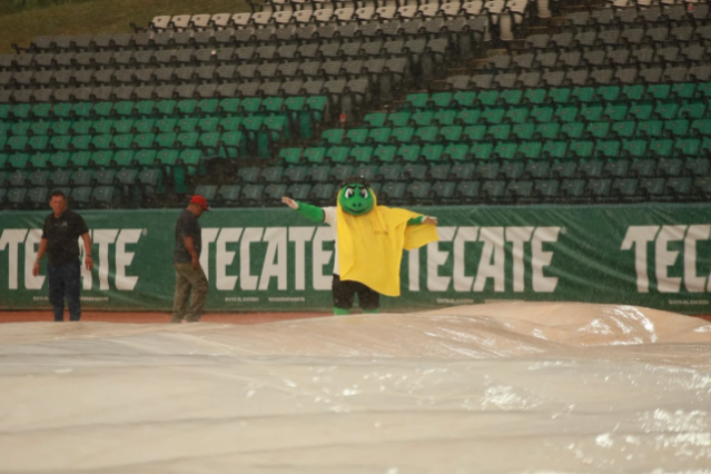 Staff del estadio protegiendo al diamante de la lluvia