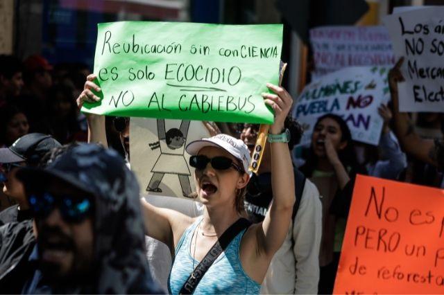 Una mujer con una pancarta, protesta por el proyecto del cablebús en Puebla