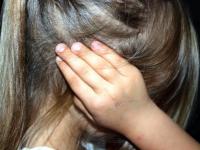 Niña de espaldas tomándose los oídos  