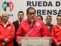 Personas en conferencia de prensa con camisa del PRI