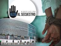 Manos atadas de persona con fachada de la FGE al fondo 