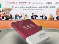 Ejemplar del Plan de Desarrollo Estatal frente a funcionarios  