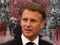 En primer plano, Emmanuel Macron, presidente de Francia; al fondo, protestas ciudadanas