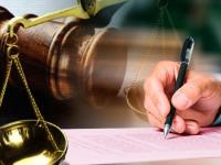 balanza con mano escribiendo sobre un documento 