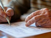 Adulto mayor firmando un testamento