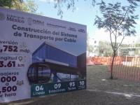 Lona con datos del cablebus de la ciudad de Puebla junto a un árbol