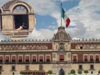 Palacio Nacional y en una ventana una mujer tomando el sol