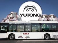 Camión eléctrico con logo de la empresa Yutong atrás y fajos de billetes a su alrededor 