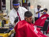 Barbero cortando el cabello a joven