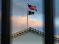 Bandera de Estados Unidos a través de unos barrotes de la Casa Blanca