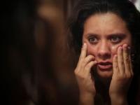 Foto ilustrativa de violencia contra una mujer que se mira al espejo y se toca el rostro